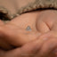 a person holding a tiny heart ring in their hand