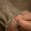 a person holding a tiny gold ring in their hand