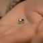 a small silver heart shaped ring on a person's hand
