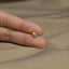 a person's hand holding a tiny yellow and silver ring