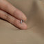 a person's hand holding a tiny silver ring