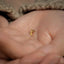 a person holding a tiny gold ring in their hand