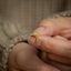a person holding a gold ring with a diamond on it