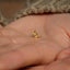 a person's hand holding a tiny gold ring
