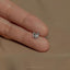 a person's hand holding a tiny diamond ring