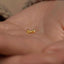 a person&#39;s hand holding a tiny gold nose ring