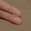 a person&#39;s hand holding a tiny silver bow ring