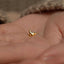 a small gold bird stud on a persons hand