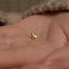 a small gold bird stud on a persons hand