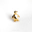 a gold penguin brooch sits on a white surface