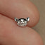 a small silver cat charm sitting on top of a persons finger