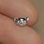 a small silver cat charm sitting on top of a persons finger