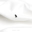 a black bird sitting on top of a white sheet