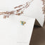 a pair of earrings sitting on top of a white box