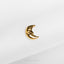 a small gold crescent brooch sitting on top of a white cloth