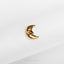 a small gold crescent brooch sitting on top of a white cloth