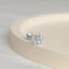 a pair of silver flower earrings sitting on top of a white surface