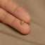 a person's hand holding a tiny yellow diamond