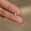 a person&#39;s hand holding a tiny cross ring