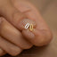 a woman's hand holding a tiny gold ring