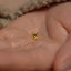 a person's hand holding a tiny gold nose ring