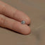 a person&#39;s hand holding a tiny silver bead