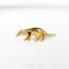 a gold brooch depicting an animal on a white background