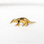 a gold brooch depicting an animal on a white background