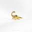 a gold brooch depicting a dinosaur on a white background