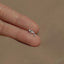 a person&#39;s hand holding a tiny silver dolphin ring
