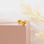 a pair of gold earrings sitting on top of a pink box