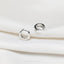 a pair of silver rings sitting on top of a white cloth
