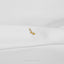 A small gold earring with a floral design is resting on a white fabric surface.