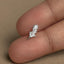 A small silver leaf-shaped earring is being held between two fingers.