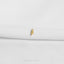 A single gold leaf pin is displayed on a white fabric surface.