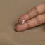 A person's left hand is holding a small silver earring with a leaf-like design.