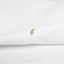 A small gold-colored pin or brooch is resting on a white fabric surface.