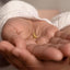 A close-up image of a person's hand holding a small gold earring.