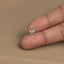A person's hand holding a small silver flower-shaped earring between the fingers.