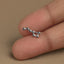 A close-up image of a person's thumb holding a small silver earring with a star-shaped design.