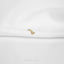 A single gold earring with a star-like design is resting on a white fabric surface.