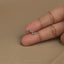 A close-up image of a person's hand holding a small, silver earring on the index finger.