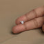 A person's thumb holding a small silver dog tag with the text "dog dad" on it.