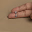 A person&#39;s fingers holding a small silver charm on the tip of the index finger.
