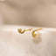 A pair of gold earrings with a crescent moon design and a small gemstone on each side, displayed on a white marble surface.