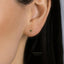 A close-up of a person's ear with a small green gemstone earring.