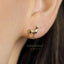 A close-up of a person's ear wearing a gold-colored earring shaped like a small llama.