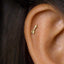 A gold-colored earring with an arrow-shaped design is visible in the ear.