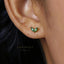 A close-up of a person's ear with a small green leaf-shaped earring.