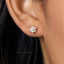 A close-up of a person's ear wearing a small, delicate earring with a flower-shaped design and white stones.